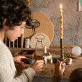 Load image into Gallery viewer, Child interacting with small figurines and crystals on a wooden table with a candle in the background.
