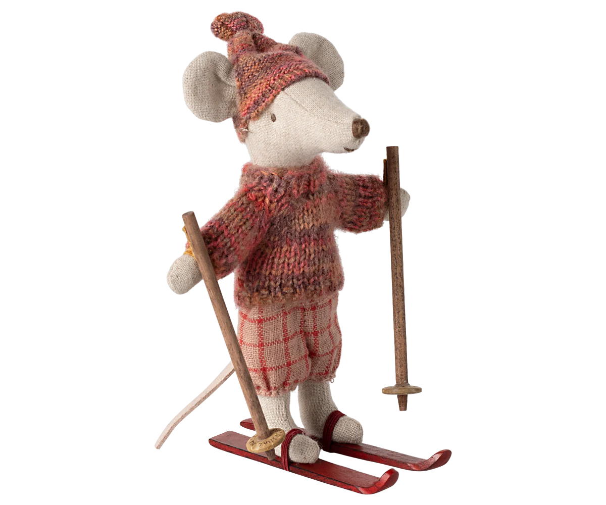 Toy mouse in skiing attire with a sweater, hat, and skis on a white background